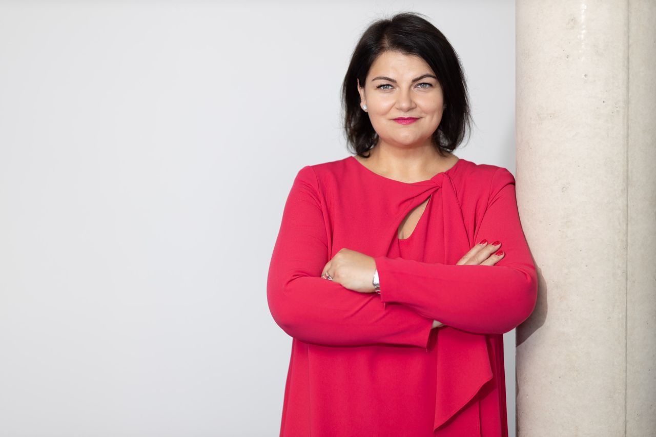 Porträt von Ramona Meinzer im roten Kleid an einer Säule